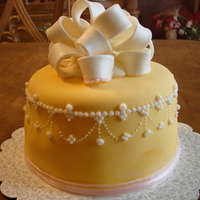 Bow Cake Chocolate cake with a peanut butter filling. Covered in yellow fondant with a fondant bow and butter-cream pearl tiara border.