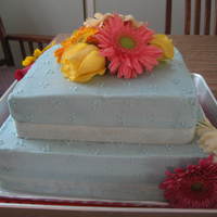Jack And Jill Cake Buttercream frosting with real roses and gerber daisies and ribbon around the bottom.