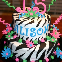 Colorful Zebra Birthday Cake Yellow cake with buttercream icing and fondant trim.Flowers, swirls, name and 15 are fondant.