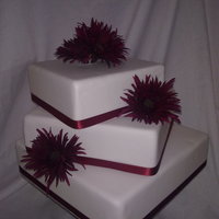 Gerbera Daisy Cake Three tier square cake with silk flowers.