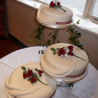 3 Tier Roses And Ivory Drapes Cake Handmade sugar roses as toppers on individual ivory cakes with fabric look swags draping down.