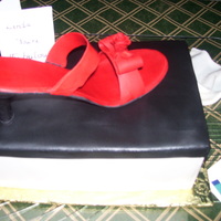 Red Shoe This is a grand fudge cake in life size shoe box with a gumpaste red shoe on top, half and half tissue paper and fondant sides and lid. The...