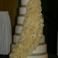 Gold Elegance Eight layers of ALL real cake covered in fondant with 100 real roses cascading down the front that were all dusted with edible gold glitter...