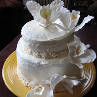 Orchid Birthday Cake gum paste orchids on a two- tiered cake with buttercream frosting.