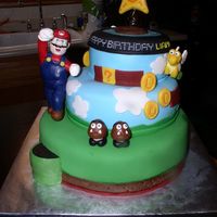Mario Birthday White vanilla cake, strawberry preserves filling, vanilla buttercream.Covered in fondant, layered & textured to mimic the Super Mario...