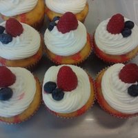 Raspberry Poke Cupcakes Raspberry Poke Cupcakes with Raspberry Vanilla Buttercream Frosting and fresh Raspberries and Blueberries.