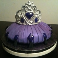 Tiara On Purple Pillow Cake Tiara is made out of white chocolate, and gems are poured sugar. Cake is a carved red velvet covered with fondant. Tassels are gumpaste.