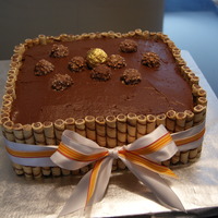 Chocolate Cake Chocolate cake with chocolate mocha buttercream topped with ferror rochers and wrapped in pirouline cookies.