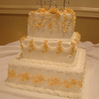 Square Traditional Wedding Cake Three tiered square cake with butter cream icing. Each layer a different sign with a soft peach color butter cream. The angle of the photo...