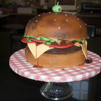 Hamburger With Cheese And The Works I made this for my husbands aunt's BBQ, they loved it. BC colored brown and airbrushed. Fondant lettuce, tomato, pickles and cheese....