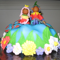 A Day In The Enchanted Flower Eden fairies made out of fondant sitting atop a mound surrounded by flowers and leaves