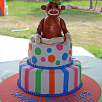 Sock Monkey Cake Two-tiered fondant cake w/ polka dots and stripes. Sock monkey is made of rice crispy treats covered w/ modeling chocolate.