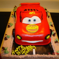 Lightning Mcqueen Cake Hand carved from vanilla cake and covered in fondant sitting on top of half sheet cake covered in buttercream.