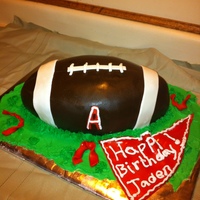 Football Birthday Cake yellow cake, chocolate buttercream covered in chocolate fondant with buttercream grass, fondand flag.