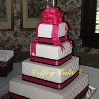 Square Buttercream Cake Buttercream iced with diamond impression, fabric ribbons around the bottom of each tier and fondant bow and streamers on top.