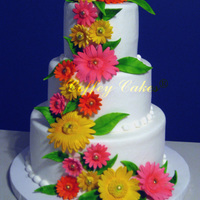 Gumpaste Daisy Cascade. The bride wanted bright neon colored Daisys with neon green leaves so I think these fit the bill.The cake is iced in buttercream.