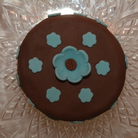 Blue Flowers 4 " round Madeira cake with chocolate brown fondant and blue fondant flowers. Just a practice cake I made.
