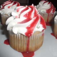 Raspberry Cupcakes White cupcakes with fresh raspberries baked inside, whipped cream icing, fresh raspberry sauce, topped with silver dragees.