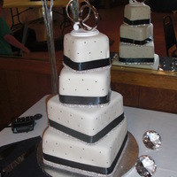 Black And White Wedding Cake With Bling 4 tiered, stacked crooked wedding cake with black ribbon.