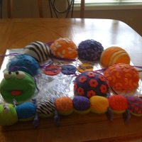 Wormie "wor mie" cake. the stuffed animal is in front of the cake.