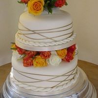 Autumn Wedding Cake Two tiers decorated with fresh roses in Autumn colours, and gold ribbon spun around the edge