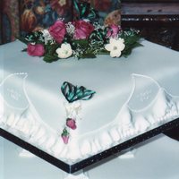 Square 2 Tier Wedding Cake Fruit cakes covered with marzipan and sugarpaste. Frilled sides with wedding bell royal iced stencilling. Handmade flowers on the top and...