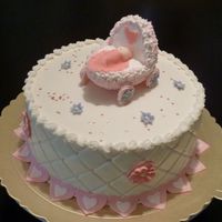 Baby Shower Cake Cradle is made of RKT covered with royal icing. Fondant baby with blanket. Buttercream iced cake with fondant hearts border.