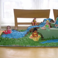 Pixie Hollow With Tinkerbell & Friends Pound cake with fondant figures and base, with a buttercream stream and royal icing grass