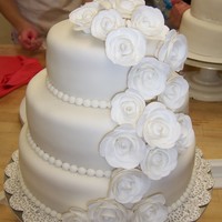 Wedding Cake Three tiered wedding cake, covered with fondant. Pearl borders, gumpaste roses.
