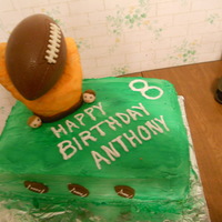 Football Birthday Cake chocolate crispy football with rice crispy treat hand/glove covered in fondant.2 layered vanilia cake with green spray coloring for the...