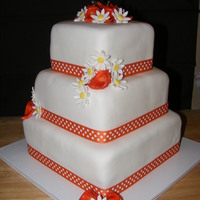 Tn Vols Themed Wedding Cake 6, 8 and 10 in square covered in white fondant. orange calla lily and daisies made from fondant. Bride wanted the polka dot ribbon around...