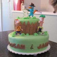Phineas And Ferb Vanilla cakes covered in MMF. Fondant fence, piped grass. Characters are toys :) Birthday cake for 2 little cousins turning 3 . TFL