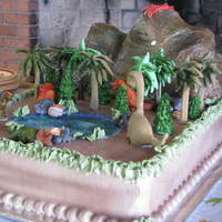 Dinosaur Cake mountain is sculpted yellow cake. base is chocolate cake. all decorations were made out of gumpaste. cake is frosted in IMBC
