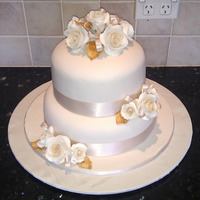 Ivory And Gold Wedding Cake Ivory fondant covered cakes, with moulded roses tinted with cream calks and gold painted leaves. Ivory ribbon detail. Top cake is...