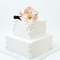 Sweet Pink Magnolia white swirly 2 tiered wedding cake, topped with pale pink gumpaste magnolia flower.swirls are made of royal icing.