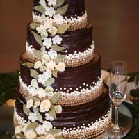 Chocolate Wedding Cake What could be wrong with a chocolate wedding cake?! The cake is covered in chocolate ganache, the flowers are white chocolate modeling...