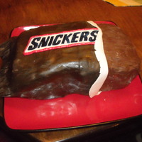 Snickers Cake White cake with melted caramel and peanuts, covered in melted chocolate with fondant "wrapper". Great tutorial under google...