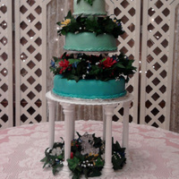 Blue Fondant Cake Graduated blue fondant cakes with silk flower arrangements between tiers and surrounding the crystal figurines.