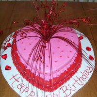 Heart-Shaped Birthday Cake Two-tier heart-shaped cake. BC frosting w/ red and pink heart sprinkles. Topper is some sort of centerpiece for Valentine's Day found...
