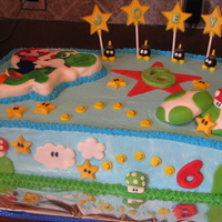 Mario And Yoshi Mario and Yoshi cake in buttercream with MMF and chocolate decorations. 3D eggs and picture backing in rice crispy, covered with MMF.