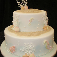 Two Tier Ocean Theme Wedding Cake This two tier Ocean themed wedding cake is decorated with hand piped coral, fondant shells and Sea Horses, piped pearls and edible sand. It...