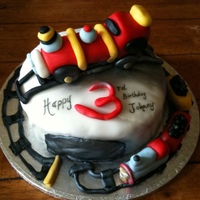 Train Birthday Cake Hi, This is a 3rd Birthday cake featuring a train and a track going around the cake board. The cake was a vanilla sponge.