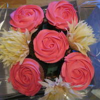 Pink Cupcake Bouquet Chocolate cupcakes, decorated with pink (frosting) rose swirls and artificial flowers.