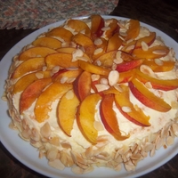 Almond- Meringue Cake Cake made from meringue rounds and covered in Italian Meringue ButtercreamTopped with Peaces/Nectarines and Sliced Almonds