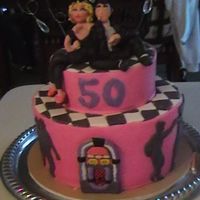 50's Grease Cake Two tiered grease themed cake covered in fondant with swing dancer silhouette , juke box and gumpaste characters on top