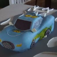 Blue Race Car car is carved out of cake then covered in fondant with gumpaste spoiler and mirrors