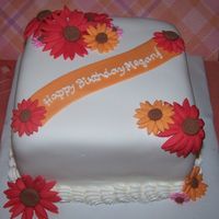 Daisy Cake Red, orange, and pink daisies. 6" square (chocolate cake, cookies 'n cream filling, vanilla BC) covered in Satin Ice Fondant.