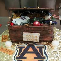 Toy Box Cake My customer requested a toy box with specific items spilling out. Chocolate cake with chocolate fondant. All edible decorations. The cars...