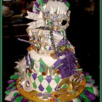 Mardigras2.jpg Cake is covered in fondx and the masks and fan are gumpaste. The coins are the chocolate foil covered kind. This was my absolute fav cake...
