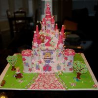 Pink Fairy Castle Iced in BC with fondant accents. Turrets are fondant and sugar cones. The green ground (grass) is done with colorflow. Trees are gumpaste...